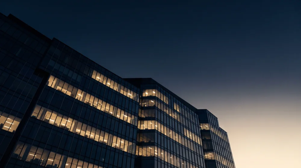 Bürogebäude zur blauen Stunde mit warm erleuchteten Fensterreihen